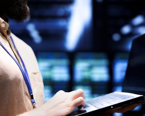 Close up shot of technician inspecting crypto mining server rigs solving complex mathematical equations. Specialist using laptop in data center housing blockchain technology high volume transactions