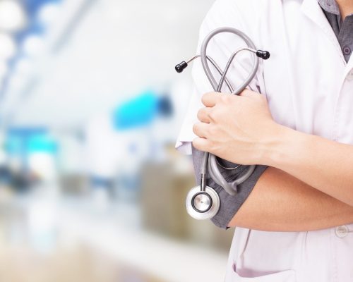 Doctor with a stethoscope in the hands and hospital background.